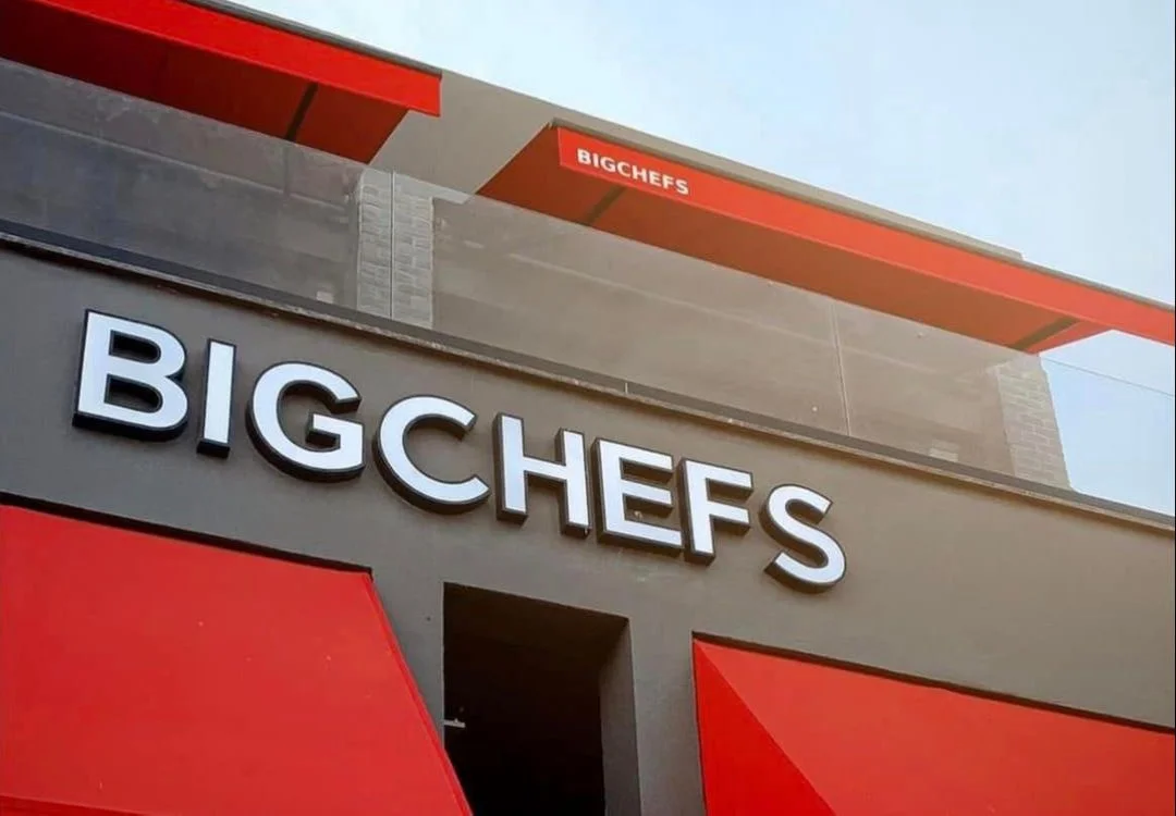White BIGCHEFS lettering on a grey façade above red awnings